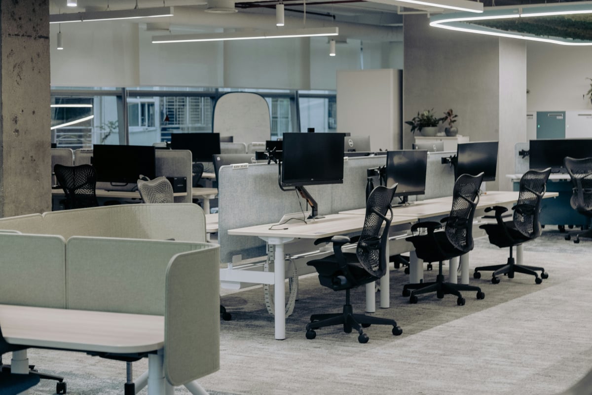 An empty modern office space with neatly arranged workstations, ergonomic chairs, and minimalistic design, highlighting the absence of employees, symbolizing labor shortages or transitions to remote work models.